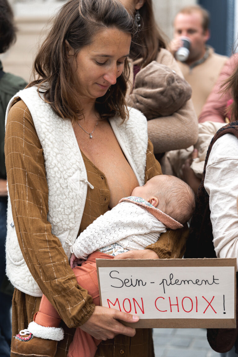 Maman qui allaite son bébé en tenant une pancarte devant la mairie de Bordeaux pendant #jaifaimjemange 2025