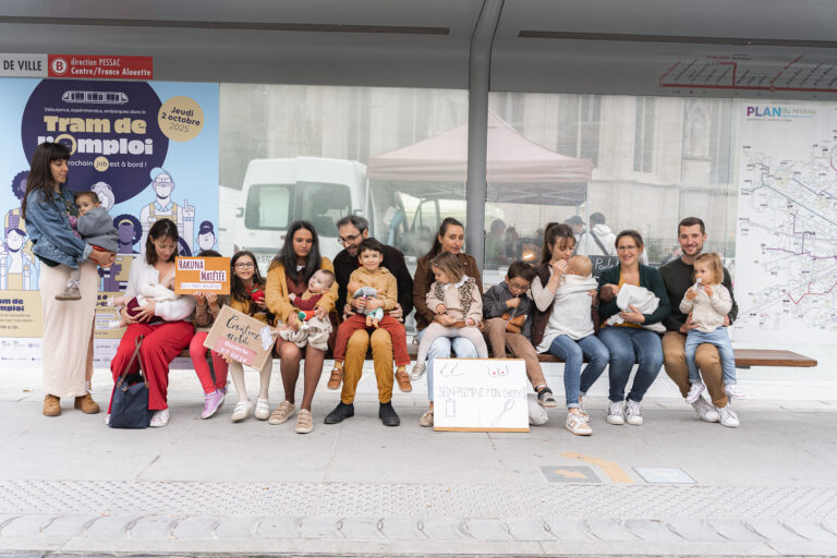 Familles avec leurs enfants et des pancartes à un arrêt de tram lors de #jaifaimjemange 2025 à Bordeaux