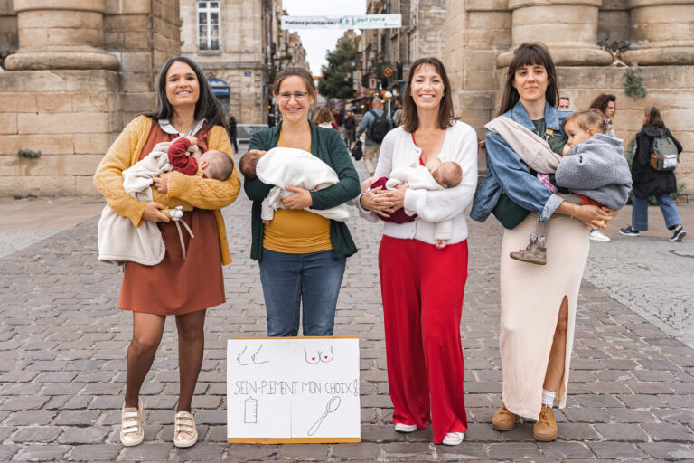 Quatre mamans qui allaitent leurs bébés devant la porte de la place de la victoire à Bordeaux avec une pancarte soutenant l'allaitement maternel lors de #jaifaimjemange 2025