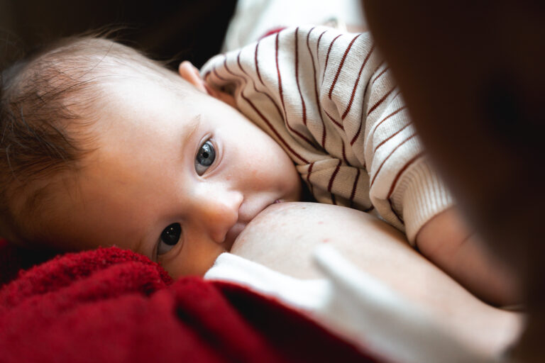 Bébé qui tète le sein de la sa maman qui l'allaite en la regardant dans les yeux au carnaval café à Bordeaux lors de #jaifaimjemange 2025