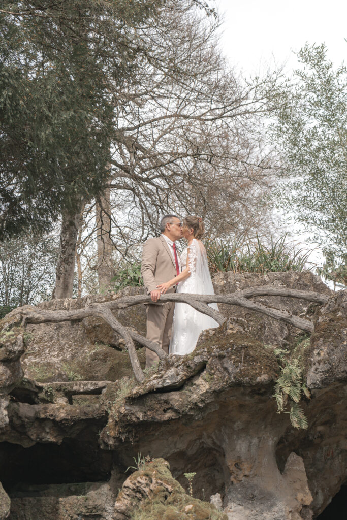 Jeunes mariés s'embrassant sur un pont en pierre au Parc de Majolan à Blanquefort lors de la séance couple de leur mariage