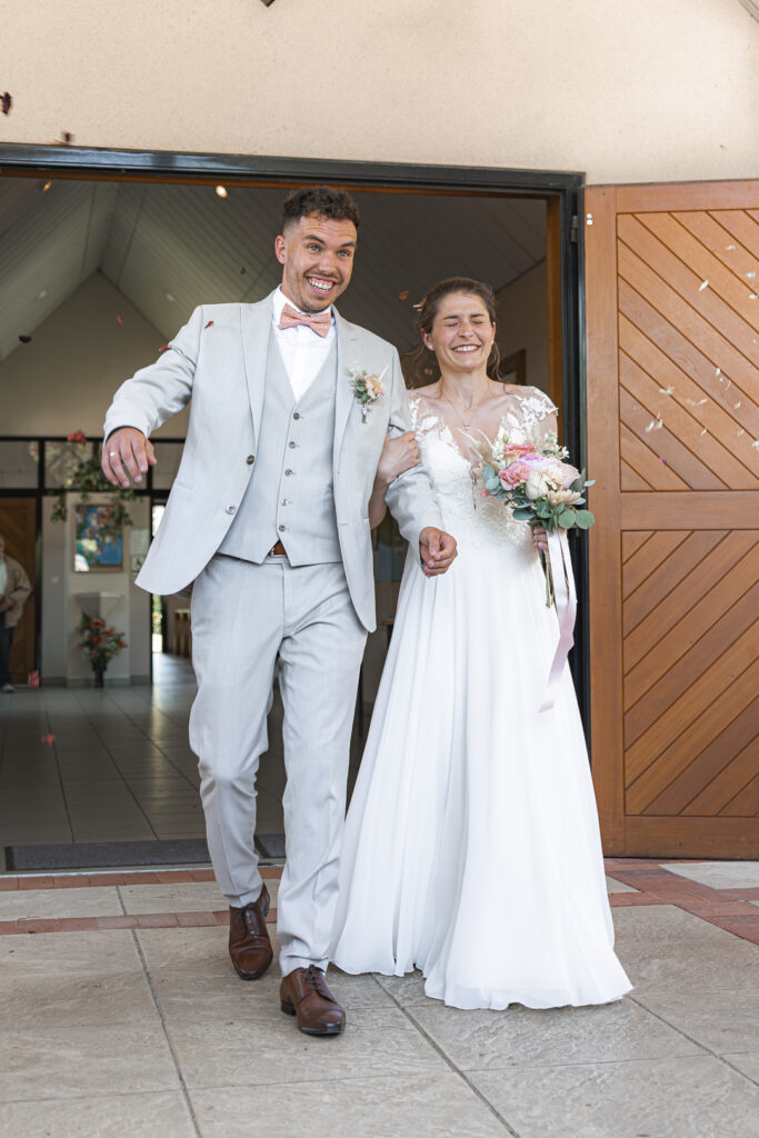 Jeunes mariés sortant de l'église sous les pétales séchés lors de leur reportage mariage