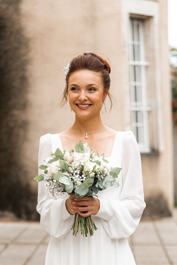 Future mariée tenant son bouquet avant son entrée à la mairie lors de son mariage