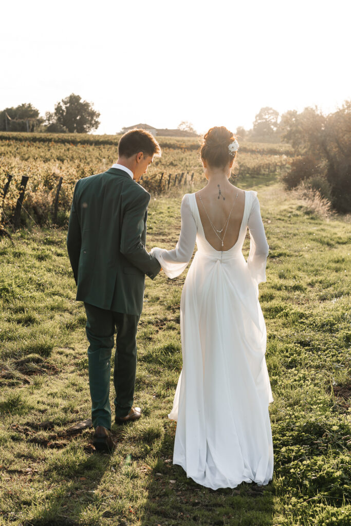 Jeunes mariés marchant dans les vignes au coucher du soleil lors de la séance couple de leur mariage