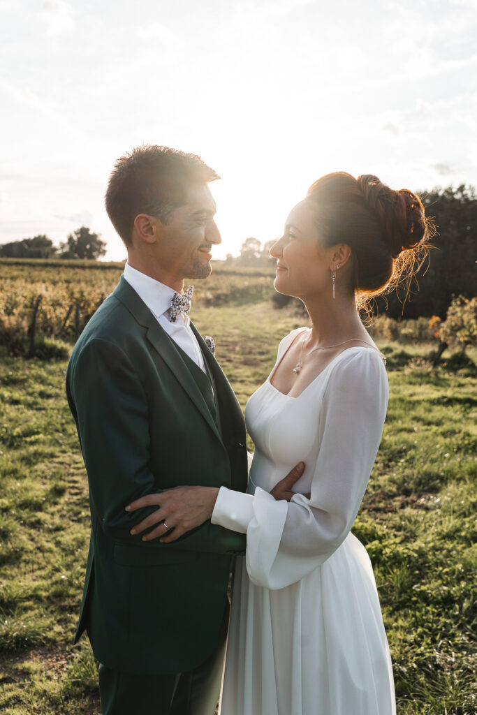 Jeunes mariés se regardant dans les yeux dans les vignes lors de la séance couple de leur mariage