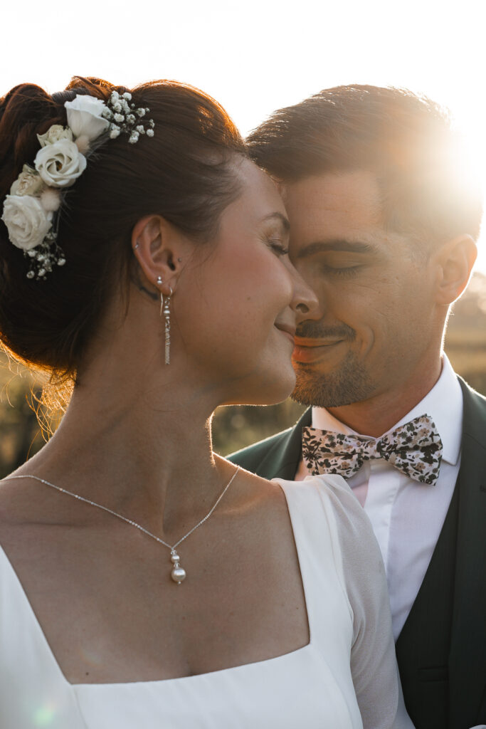 Jeunes mariés front contre front lors de la séance couple de leur mariage dans les vignes au coucher du soleil