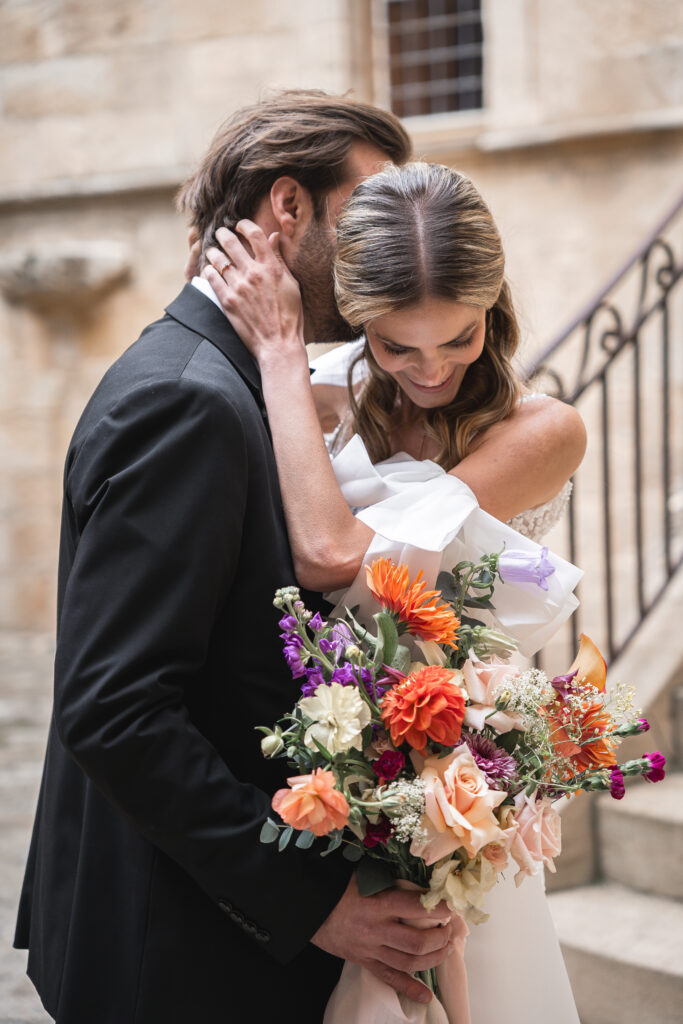 Futurs mariés qui se retrouvent après le premier regard de leur mariage et s'enlacent avec le bouquet