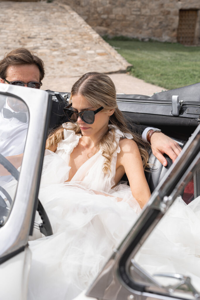 Jeunes mariés lors de la séance couple de leur mariage dans une voiture de collection