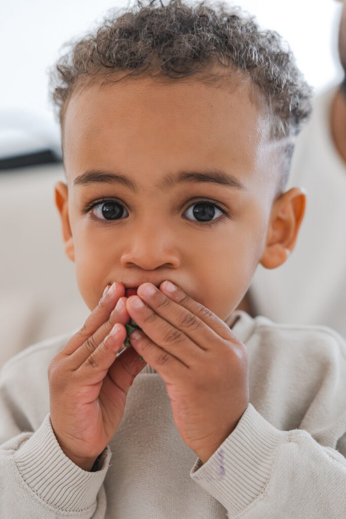 Portrait d'un enfant qui mange une fraise lors d'une séance famille lifestyle à domicile à Pessac