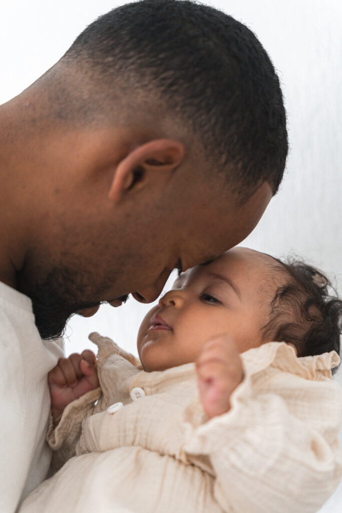 Bébé front contre front avec son papa lors d'une séance naissance lifestyle à domicile à Pessac