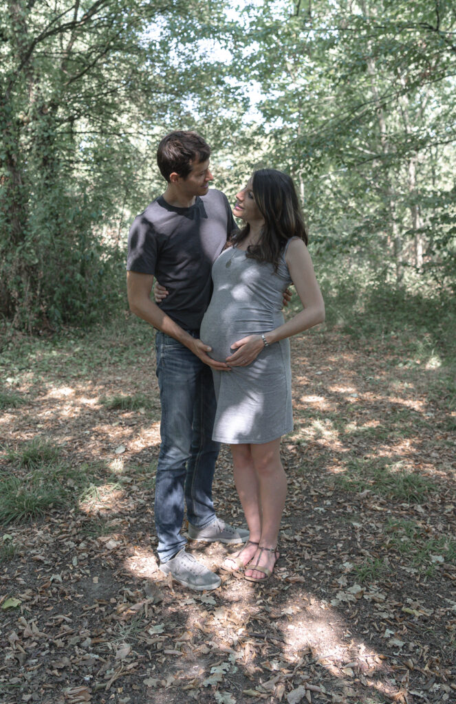Homme qui regarde sa femme enceinte yeux dans les yeux, mains sur son ventre dans la forêt du Parc Palmer de Cenon lors d'une séance grossesse