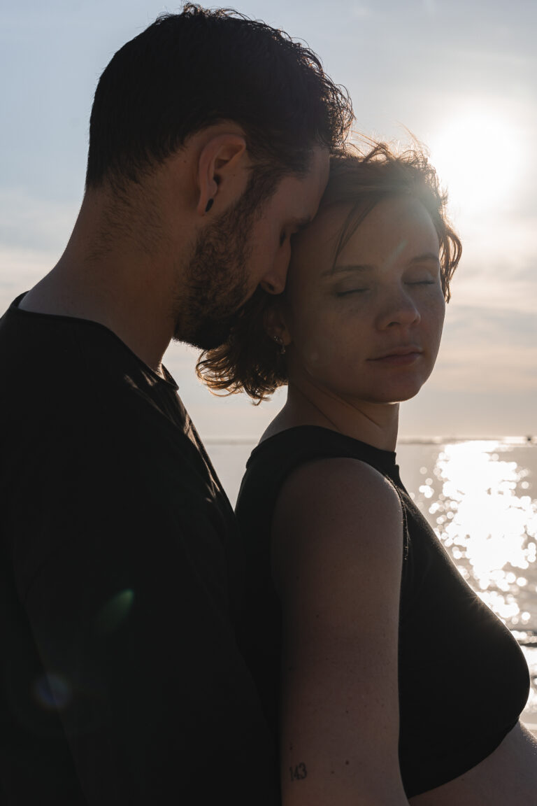 Couple front contre front devant la mer au coucher du soleil lors d'une séance photo couple en extérieur à la plage des dunes du pilat sur le Bassin d'Arcachon