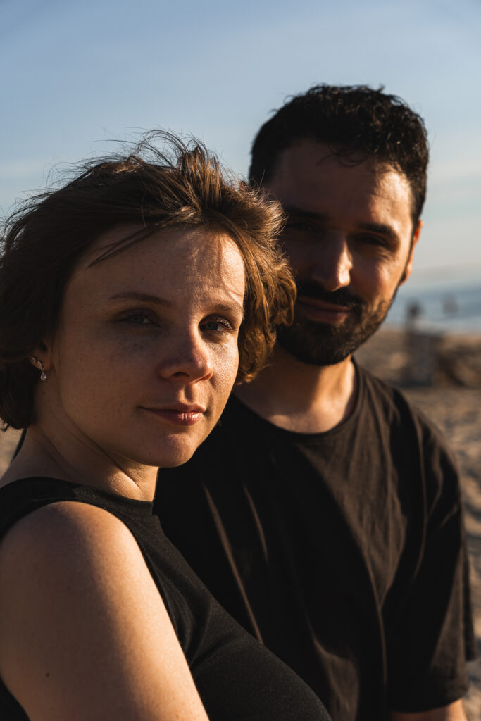 Couple qui regarde l'objectif lors d'une séance couple au coucher du soleil aux Dunes du Pilat