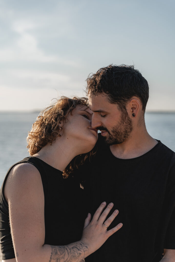 Couple qui s'embrasse devant la mer lors d'une séance couple aux Dunes du pilat