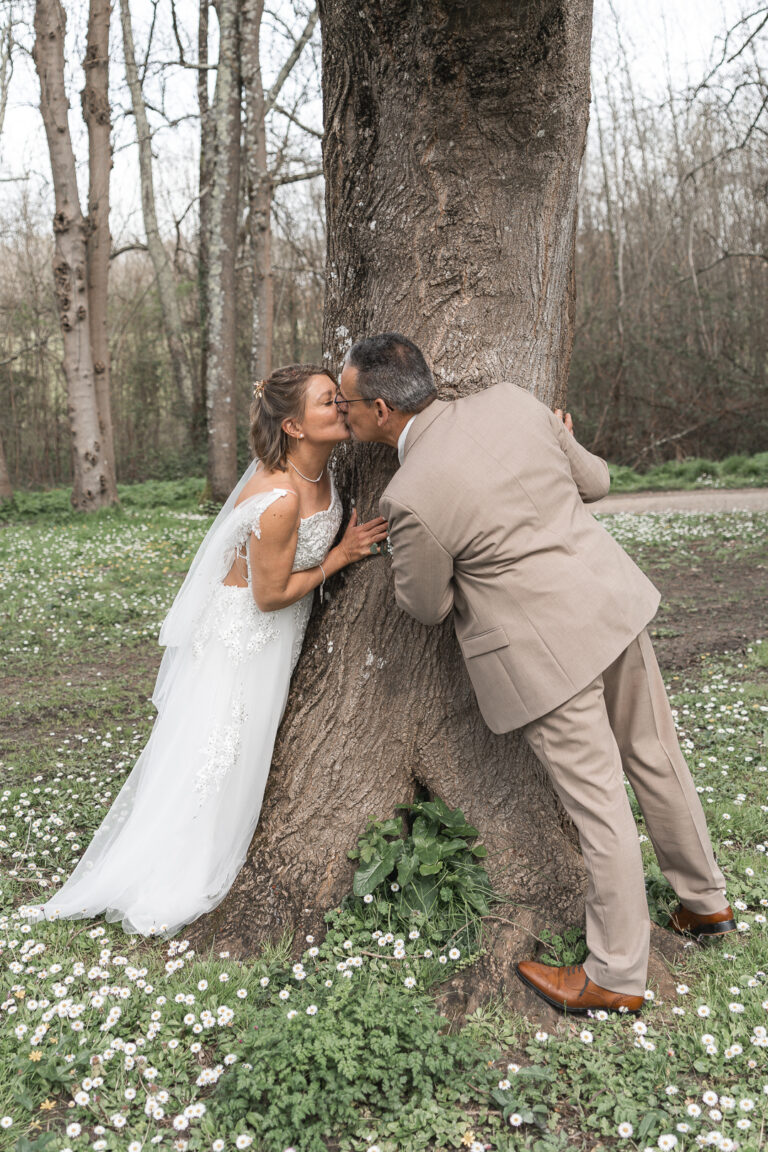 Mariés qui s'embrassent devant un arbre lors de la séance photo de couple de leur mariage civile à Blanquefort