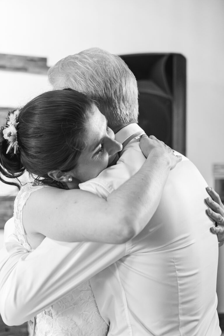 Photo en noire et blanche d'une mariée qui fait un calin à son père après un discours émouvant lors de son mariage au domaine à Bordeaux