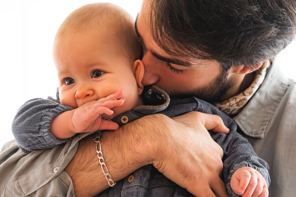 Papa qui câline son bébé avec amour lors d'une séance famille lifestyle à domicile à Mérignac