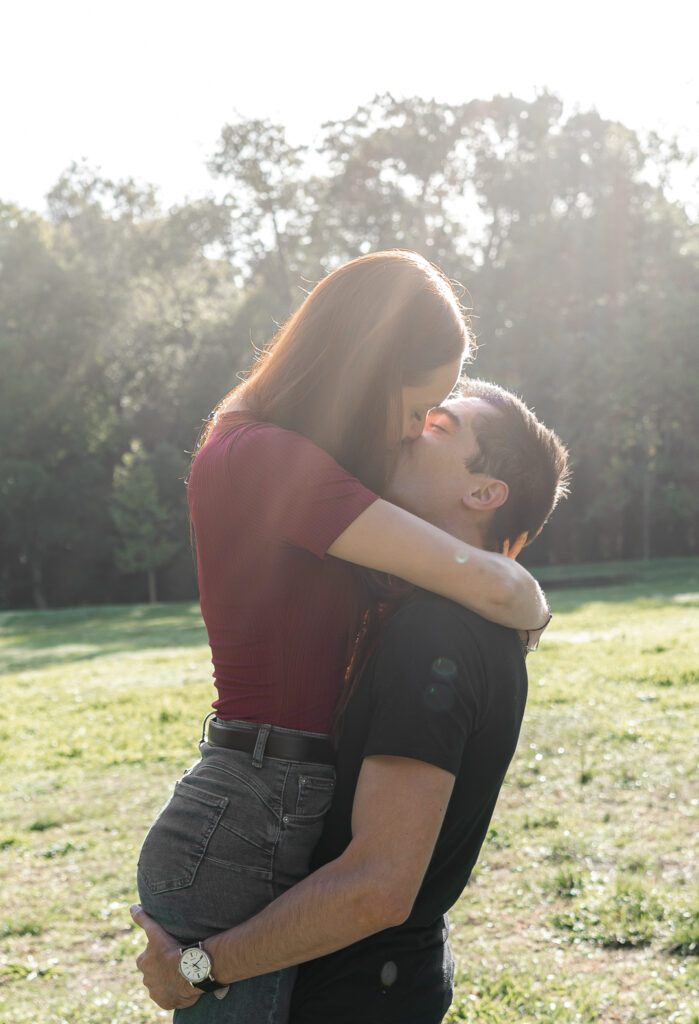 Couple qui s'embrasse sous les rayons du soleil lors d'une séance couple en extérieur au parc majolan de Blanquefort