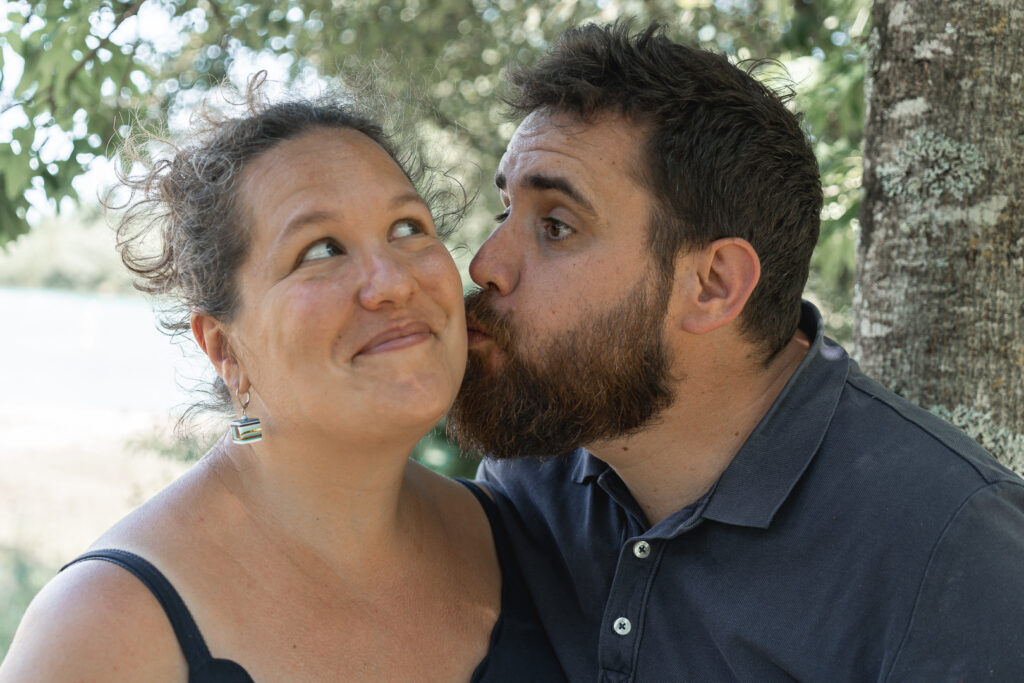 Photo de couple d'un homme qui embrasse sa femme sur la joue avec une tête rigolote