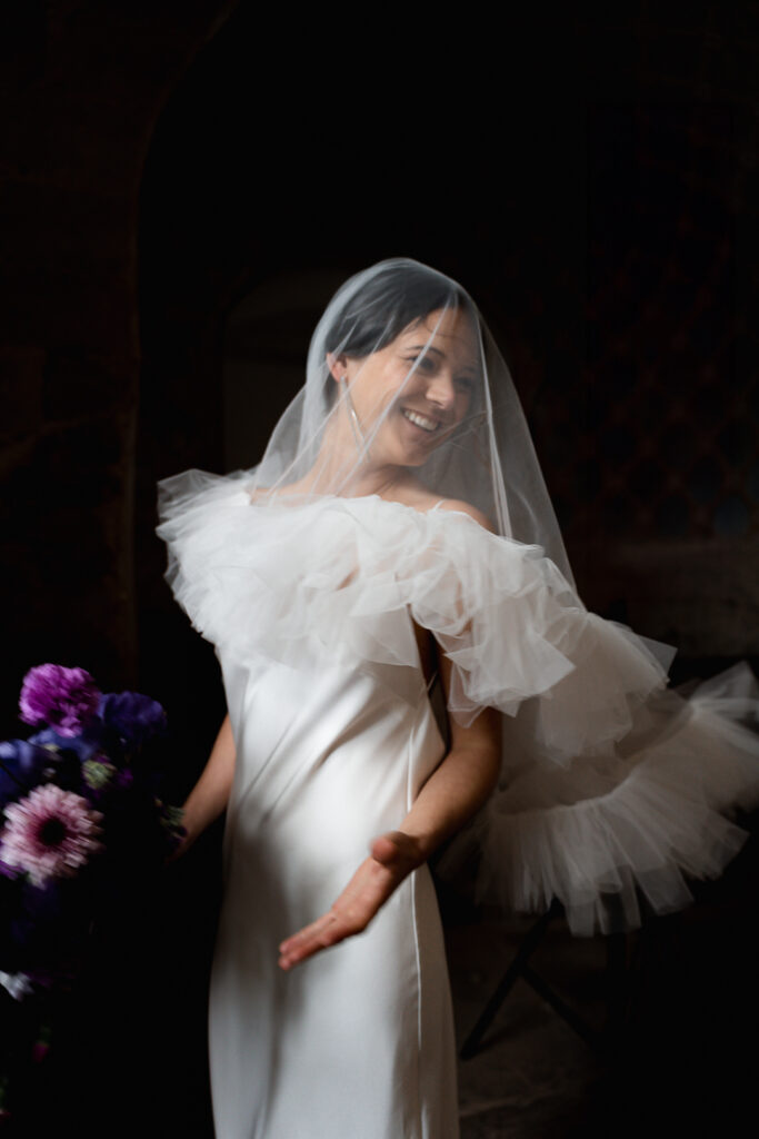 Future mariée dans sa robe qui tourne sur elle-même à l'église avant son mariage avec son bouquet son voile