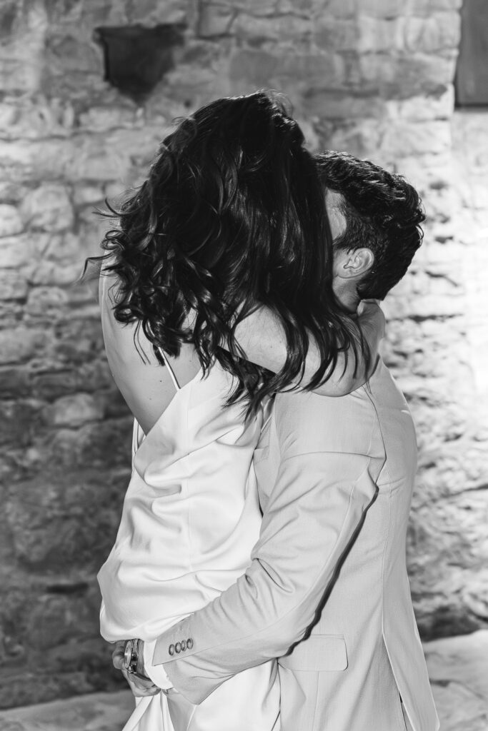 Photo en noire et blanche de jeunes mariés qui s'embrassent lors de l'ouverture de bal de leur mariage