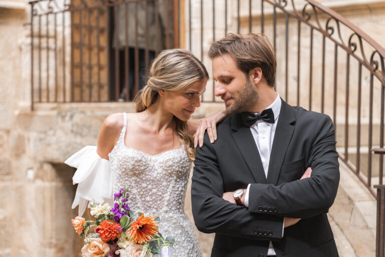 Jeunes mariés qui se regardent yeux dans les yeux devant un château lors de la séance photo couple de leur reportage mariage au chateau