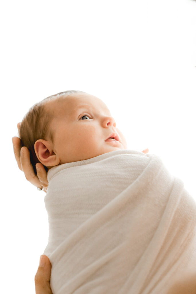 Bébé nouveau-né emmailloté lors d'une séance naissance dans mon home studio de bordeaux