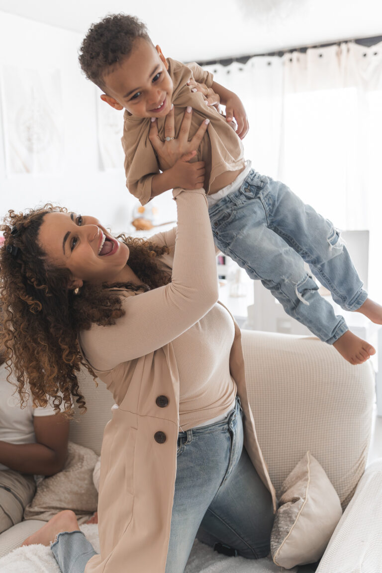 Maman qui fait voler son fils en l'air lors d'un shooting photo en famille à domicile sur Bordeaux