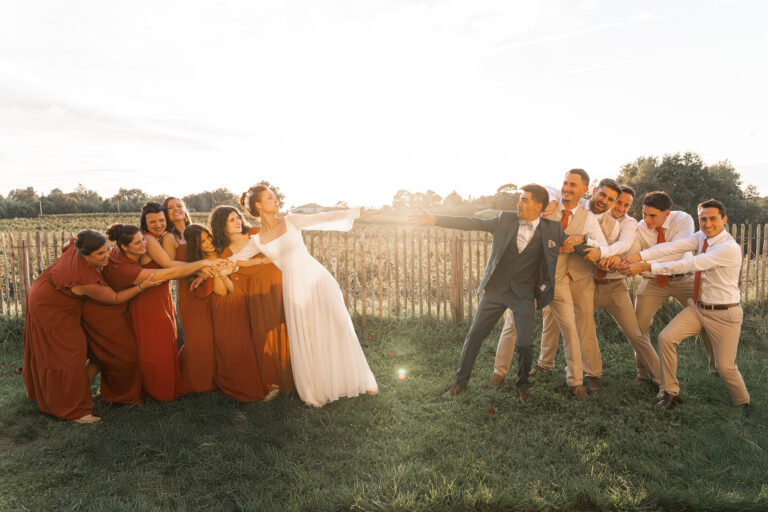 Photo de groupe des mariés que les témoins essaient de séparer au coucher du soleil lors de leur mariage à Eysines