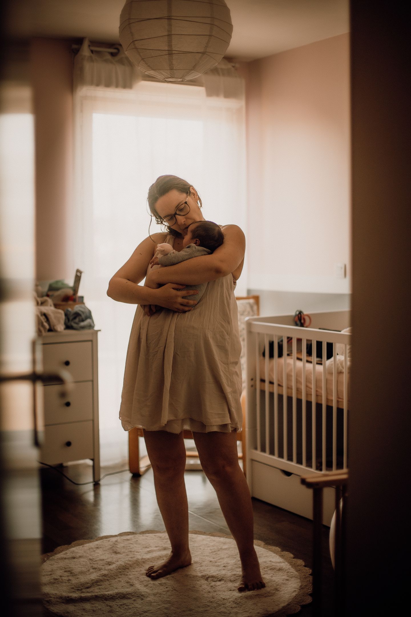 Photographe bébé professionnelle à Bordeaux avec son bébé dans les bras lors d'une séance photo de naissance à domicile