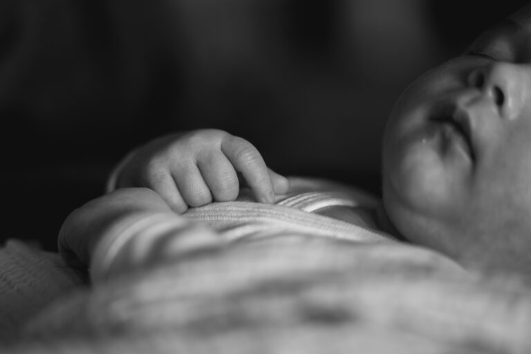 Détails sur les mains d'un bébé lors d'un shooting naissance à domicile sur bordeaux