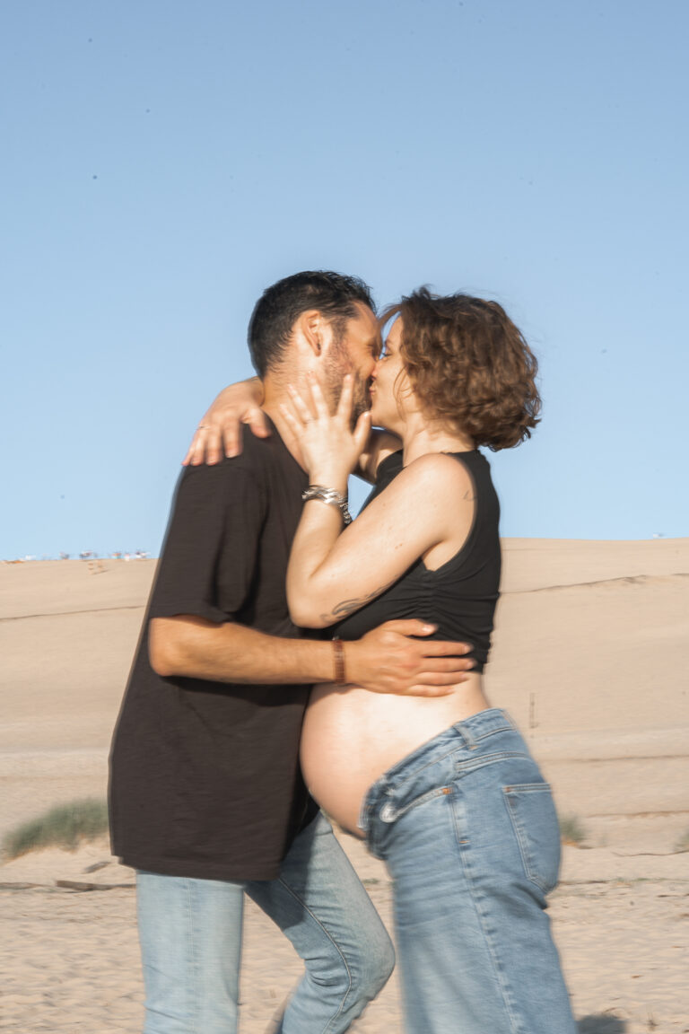 Futurs parents qui s'embrassent passionnément lors d'une séance grossesse en extérieur à la plage aux dunes du pilat sur le bassin d'arcachon