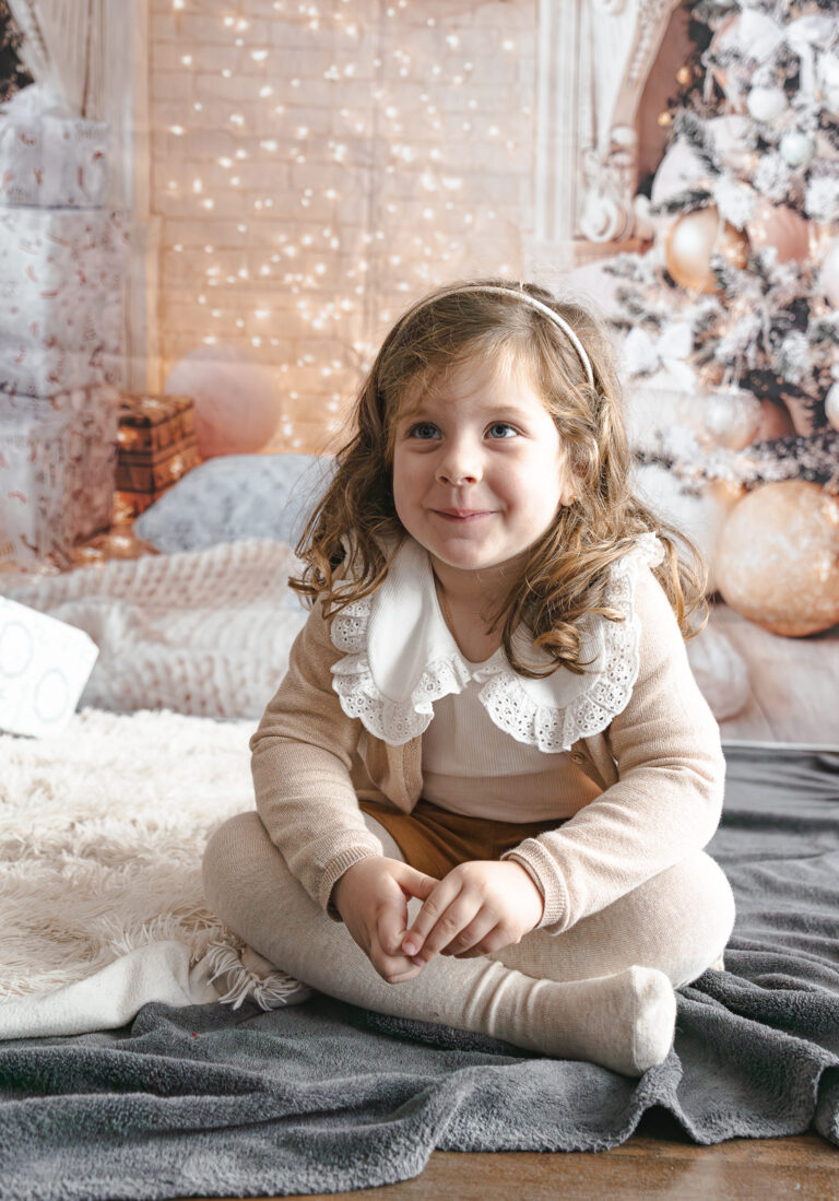 Petite fille qui sourit lors d'une mini-séance photo Noël dans mon home studio à Bordeaux