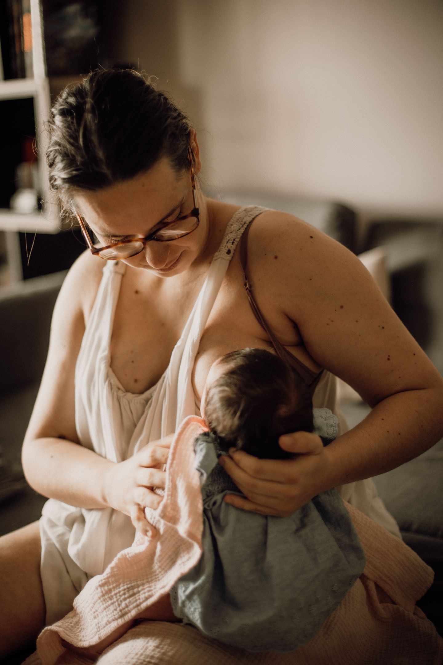 Photographe qui tient son bébé qui tète son sein pour l'allaiter à son home studio à Bordeaux