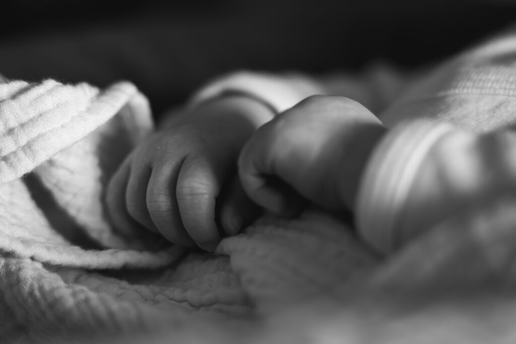 Photo en noir et blanc des détails des mains d'un nouveau-né lors d'une séance naissance au home studio à Bordeaux
