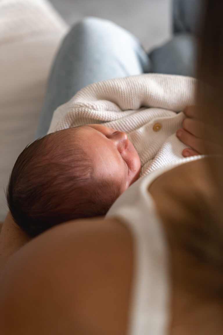Nouveau-né qui dort dans les bras de sa maman en contre plongée lors de son shooting photo bébé à domicile à Mios sur le Bassin d'Arcachon