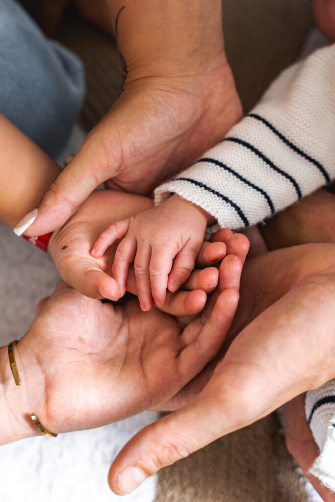 Détails des mains des membres de toutes la famille lors d'un shooting bébé à domicile à Mios sur le Bassin d'Arcachon