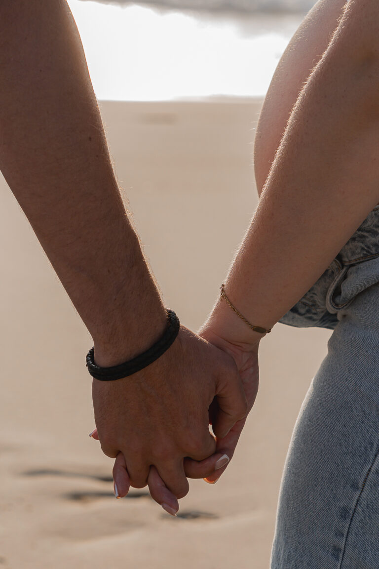 Couple qui se tient la main lors de leur séance photo grossesse sur le bassin d'arcachon