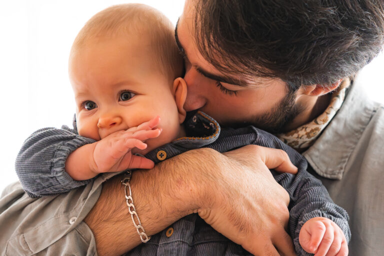 Papa qui sent le coup de sa fille en la tenant dans ses bras lors d'une séance photo famille à domicile sur Bordeaux