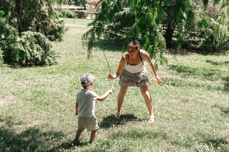 Maman qui joue à se battre avec un bâton avec son enfant lors d'un shooting photo famille en extérieur au Parc Peixotto de Talence