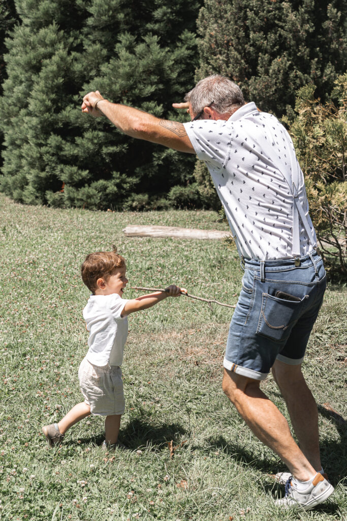Petit garçon qui joue avec son grand-père lors de leur séance photo en extérieur en famille au parc peixotto de Talence
