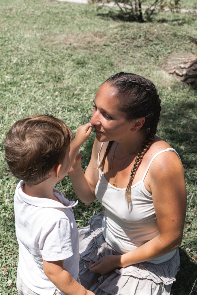 Petit garçon qui fait renifler une fleur à sa maman lors de leur séance photo famille en extérieur au Parc Peixotto de Talence