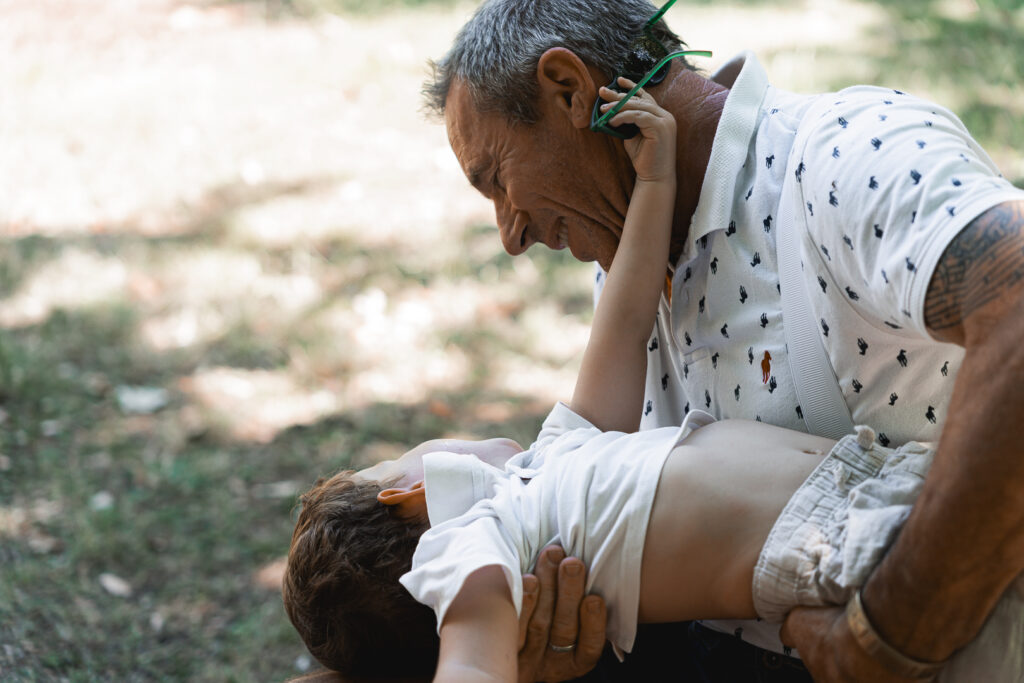 Papi qui renverse son petit-fils pour jouer lors de leur shooting famille en extérieur au Parc Peixotto de Talence