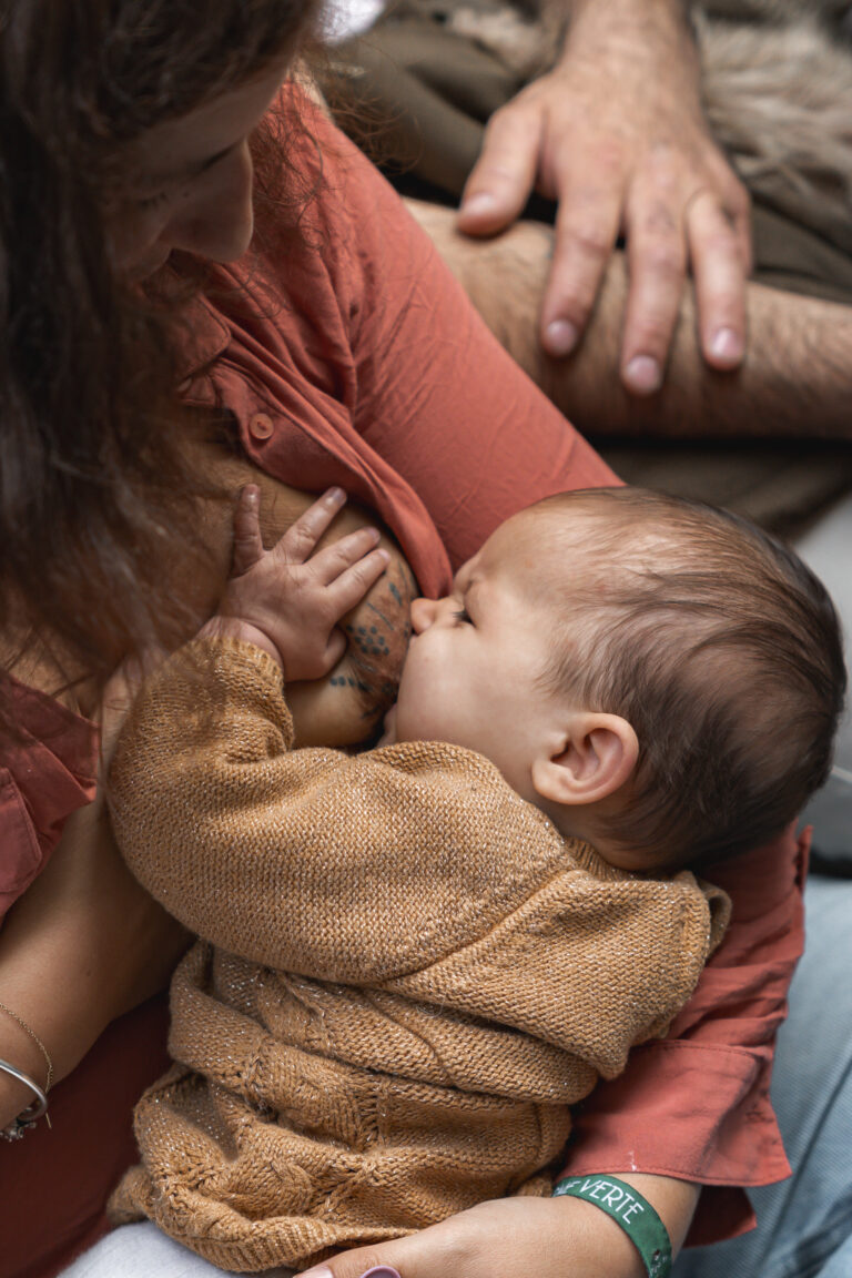 Bébé qui tête le sein de sa mère qui l'allaite en le tenant avec sa main sur la place de la bourse à Bordeaux