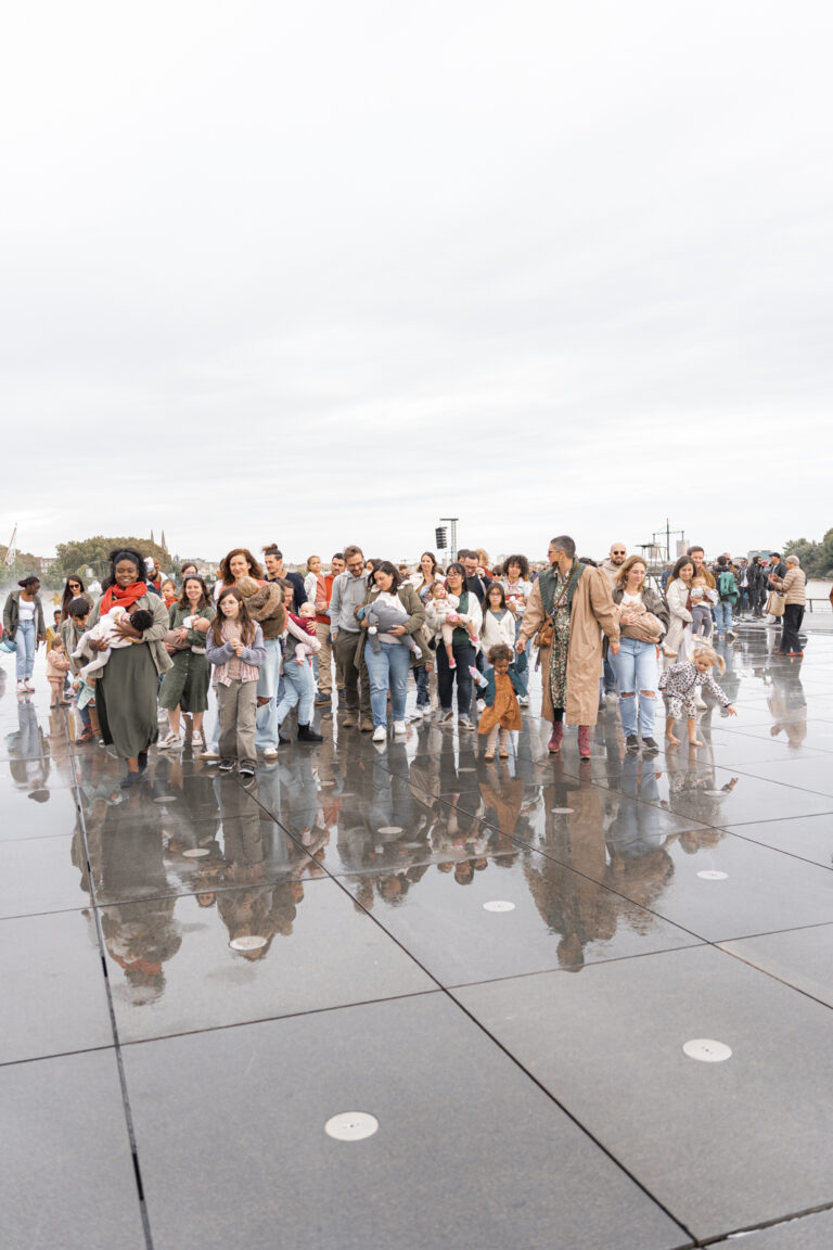 Photo collective de parents qui marchent en nourrissant leurs enfants sur le miroir d'eau de Bordeaux