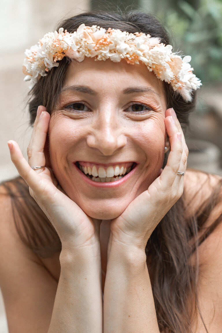Femme portant une couronne de fleurs qui entoure son visage de ses mains à maison Mandel de Bordeaux