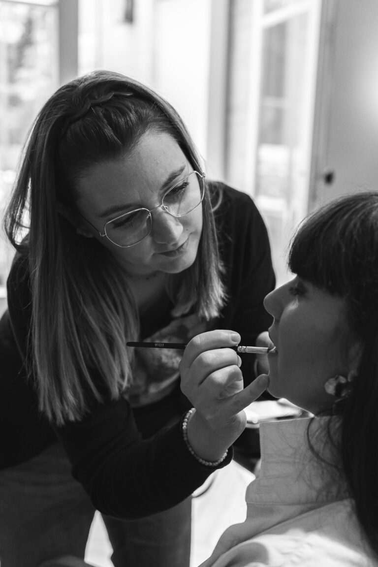 Photo en noir et blanc d'une maquilleuse qui s'occupe d'une cliente à la maison Mandel de Bordeaux