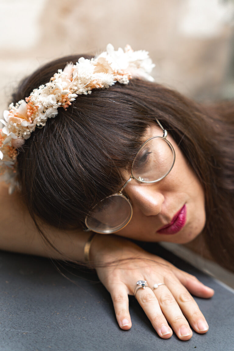 Photographe, la tête posée sur son bras qui regarde dans le vie, une couronne de fleurs sur la tête, à la maison Mandel de Bordeaux