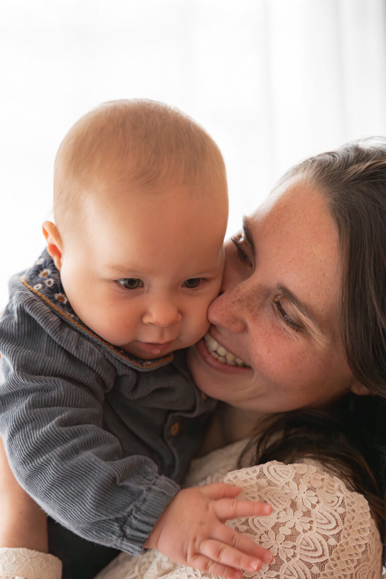 Maman qui sourit contre la joue de son bébé lors d'un shooting fête des mères au home studio à Bordeaux