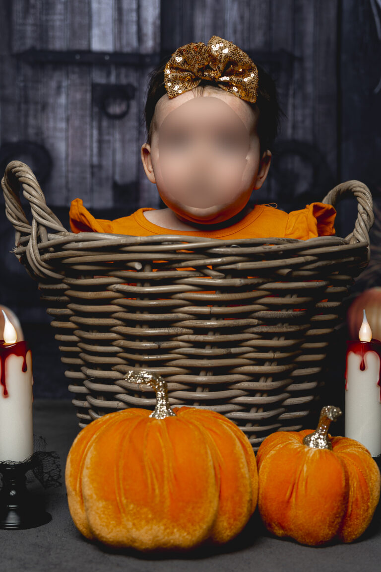 bébé déguisé en citrouille dans un panier entouré de citrouilles et bougies lors de son shooting halloween à mon home studio à Bordeaux